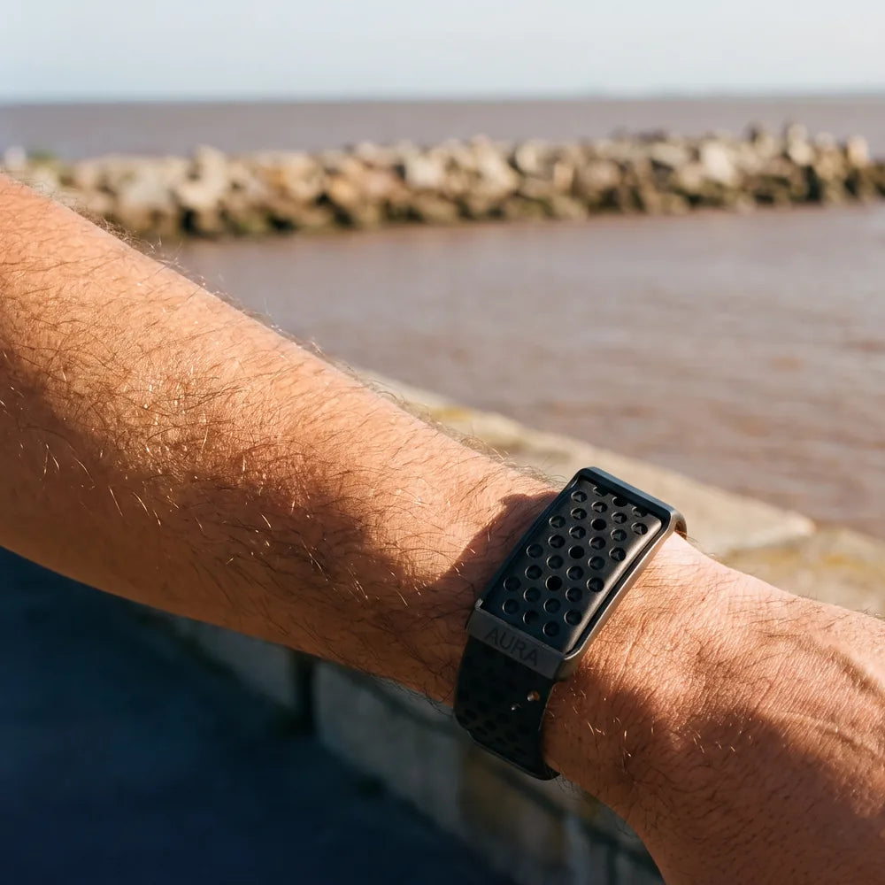 Antebrazo con la pulsera AURA apoyado en la rambla de Montevideo